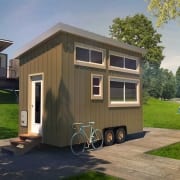 For sale: Mini home with bicycle parked in front of tiny house.