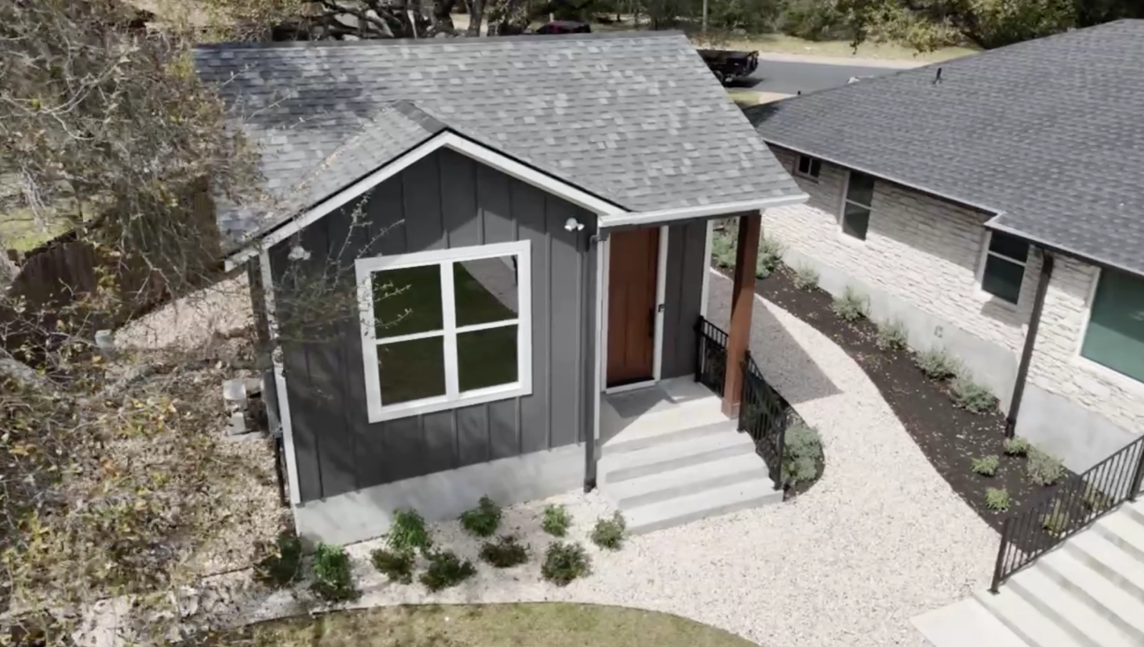 Buckthorn project beside an existing Austin home, showing side access, mature trees, and neighboring context