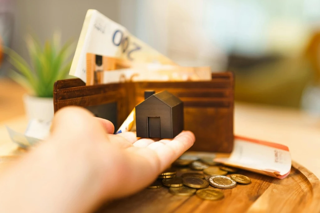 Micro home cost planning with small house model, wallet, and coins