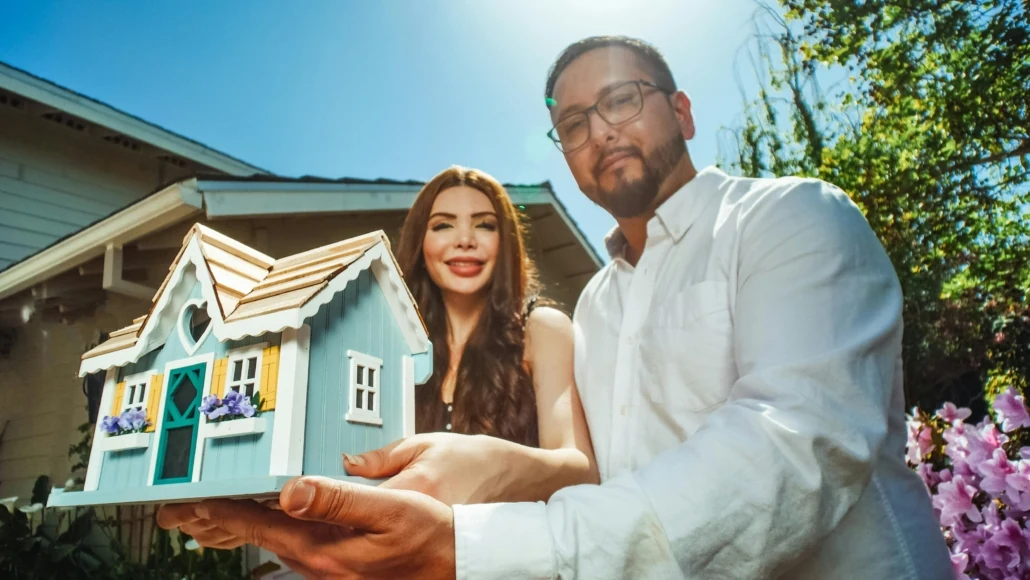 Homeowners reviewing a small house model before comparing tiny home and micro home costs
