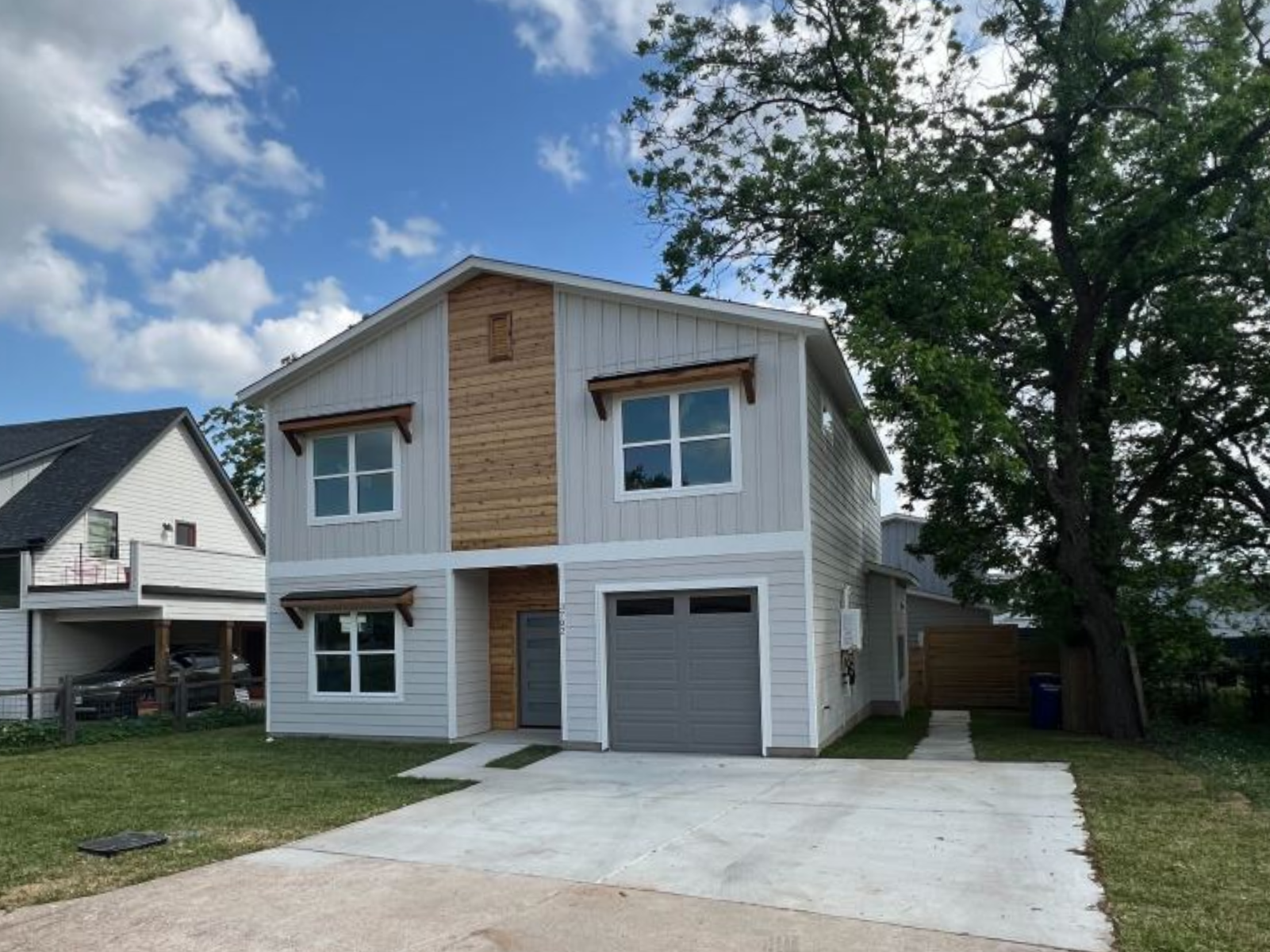 Completed Towerview Dwelling with wood entry details, garage, and project sign